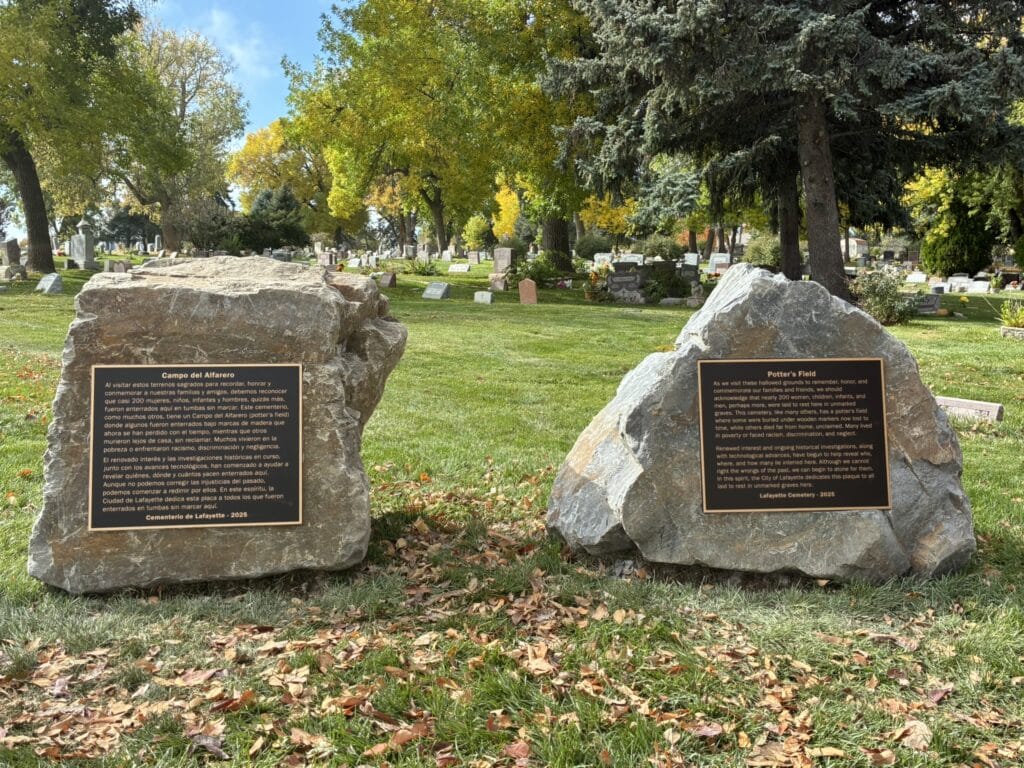 Photograph of the plaques in the Lafayette Cemetery honoring the potter's field history. There are two bronze plaques, each on their own rock of granite, one in Spanish and one in English.